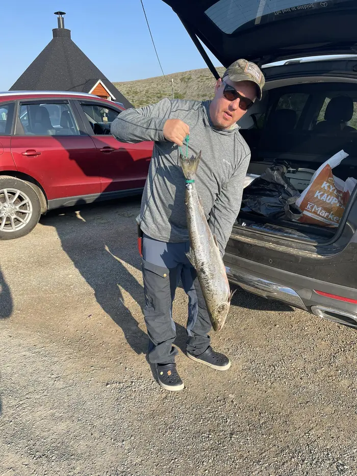 Fornøyd fisker med stor laks ved bilen